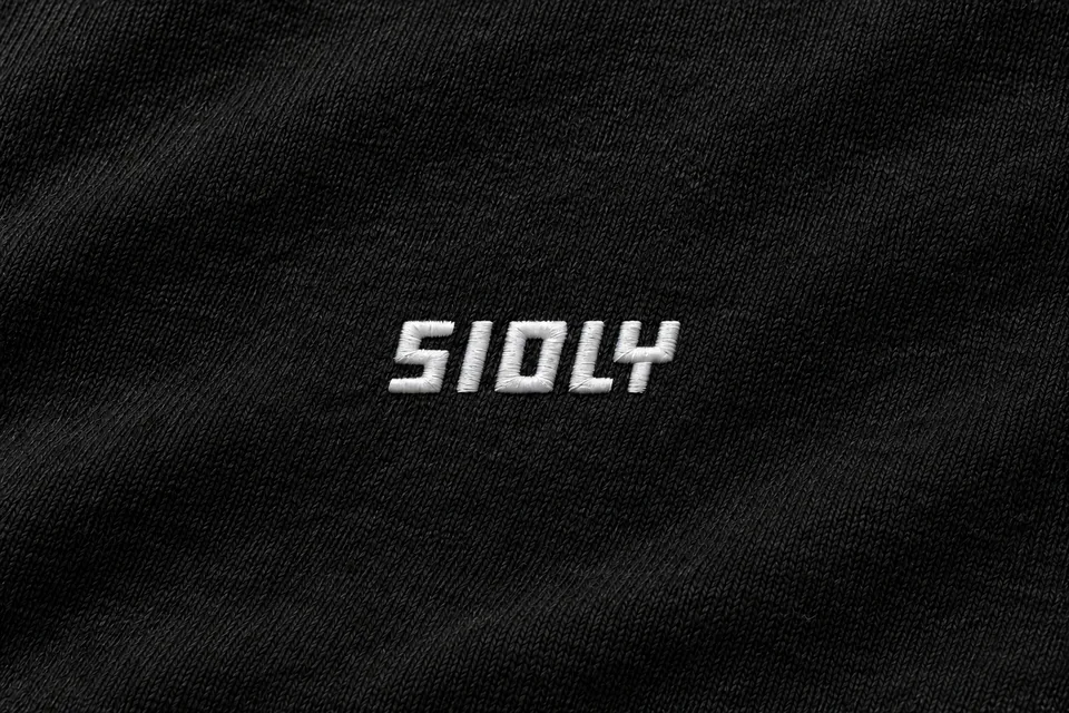 Close-⁠up of the white embroidered SIOLY logo on black fleece, pre-production visual