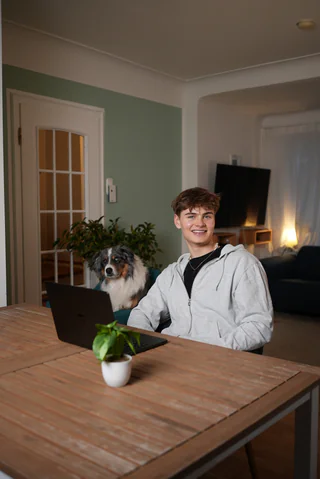 Noah at his laptop with his dog